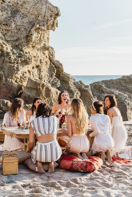 groupe de copines qui rigolent sur la plage pendant un pique nique