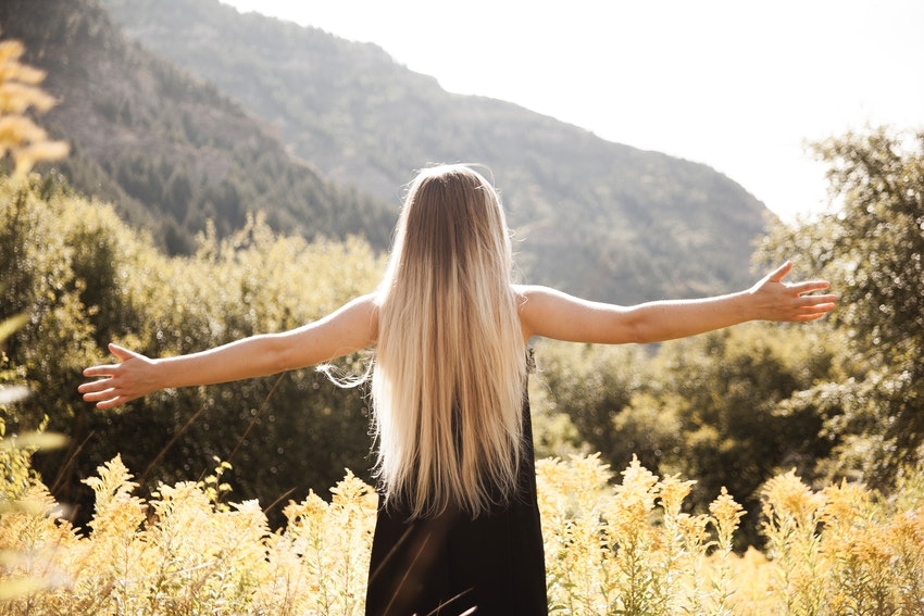 fille blonde de dos bras ouvert face a la montage